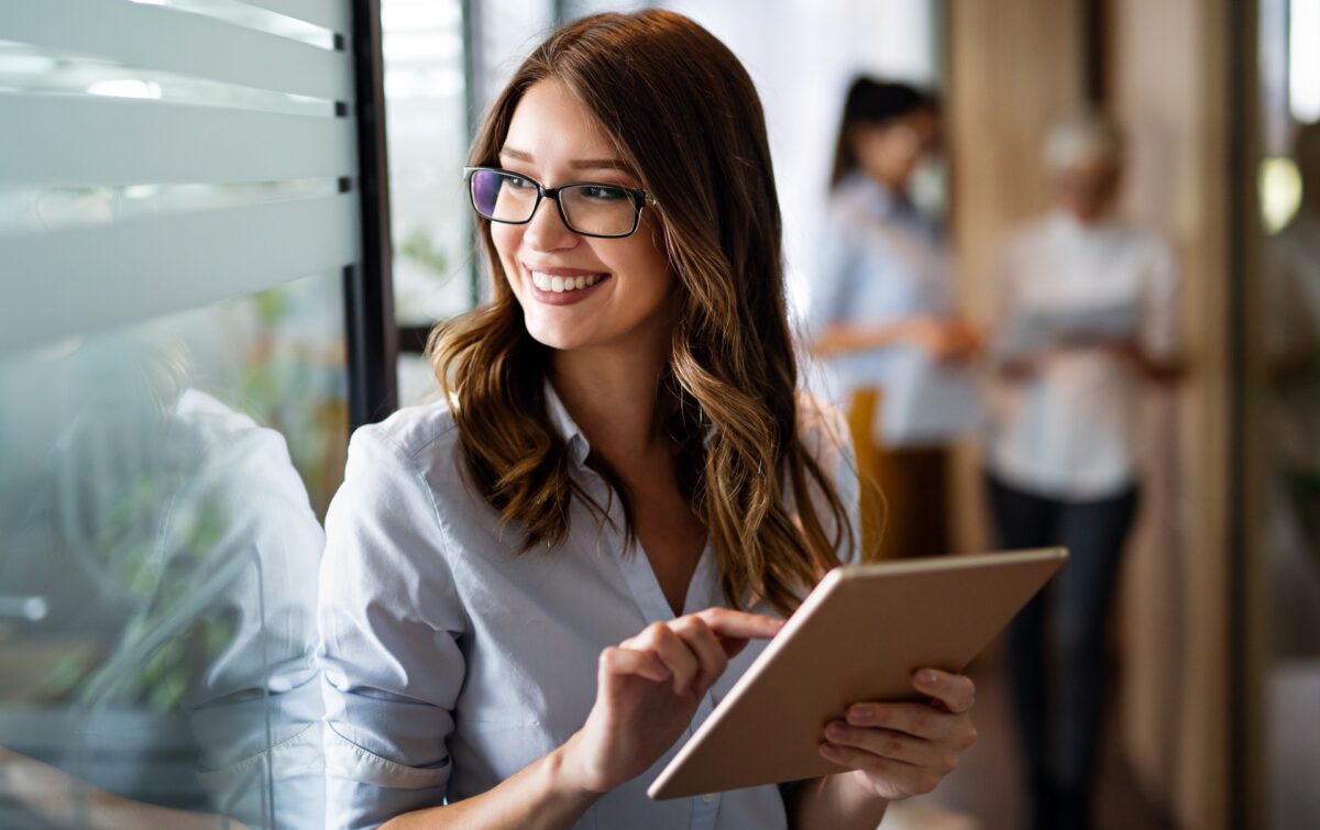 Young happy business woman working with tablet in corporate office