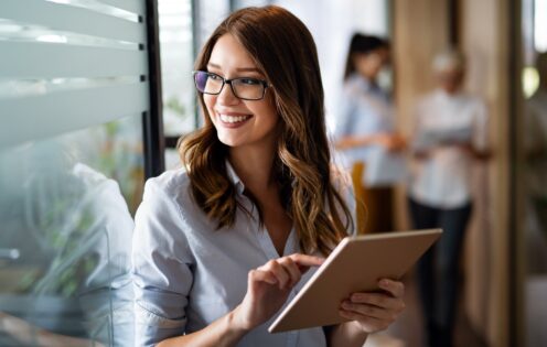 Young happy business woman working with tablet in corporate office